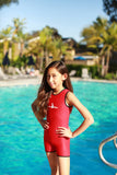 A little girl is standing by a pool wearing a red custom size Warm Belly Wetsuit.